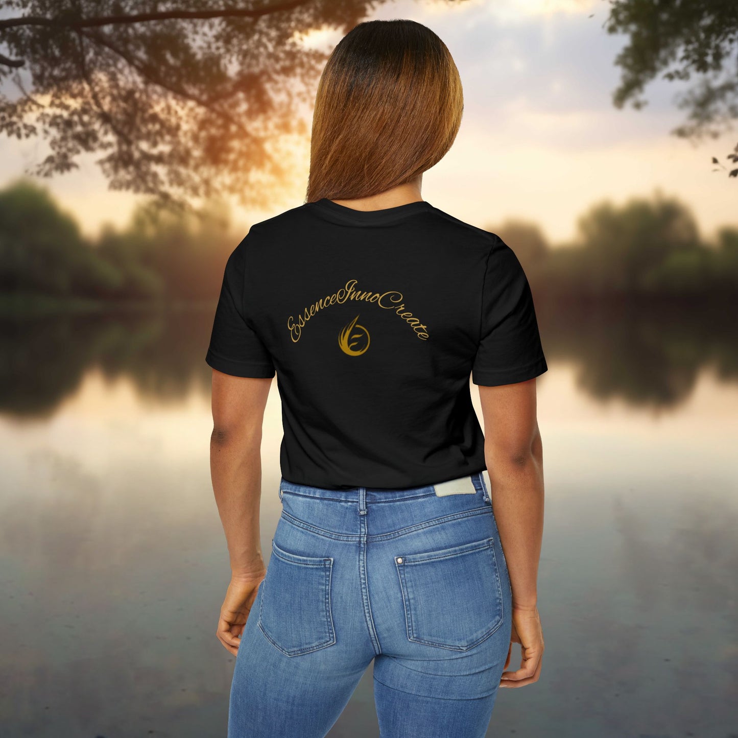 Person wearing a black t-shirt with 'EssenceInnoCreate' logo standing by a lake at sunset.