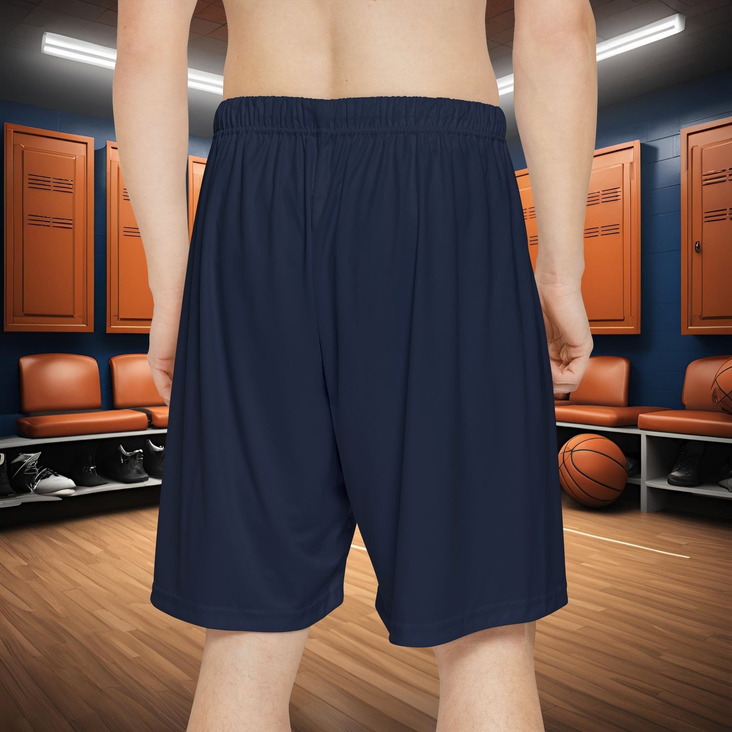Person wearing navy blue shorts in a locker room with basketballs and benches.