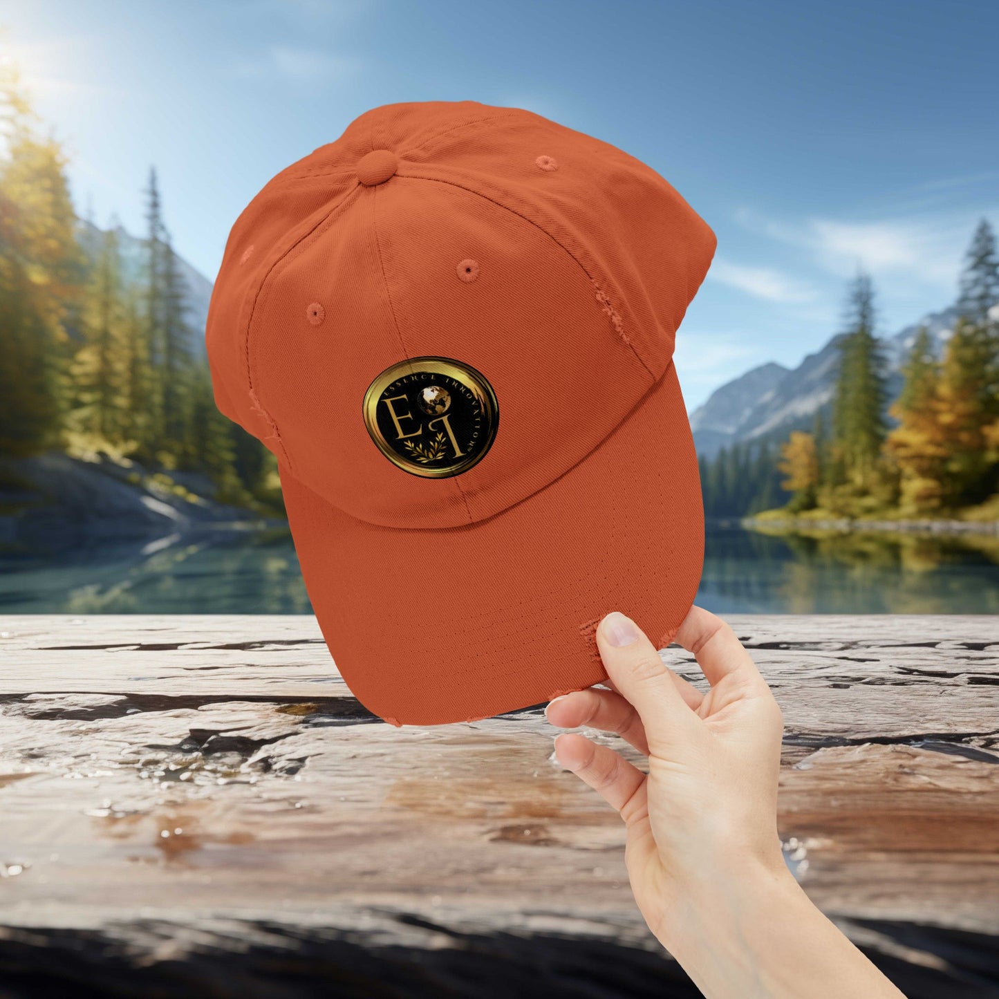 Orange Essence Innovation cap with a logo held by a hand against a scenic background of trees and water.