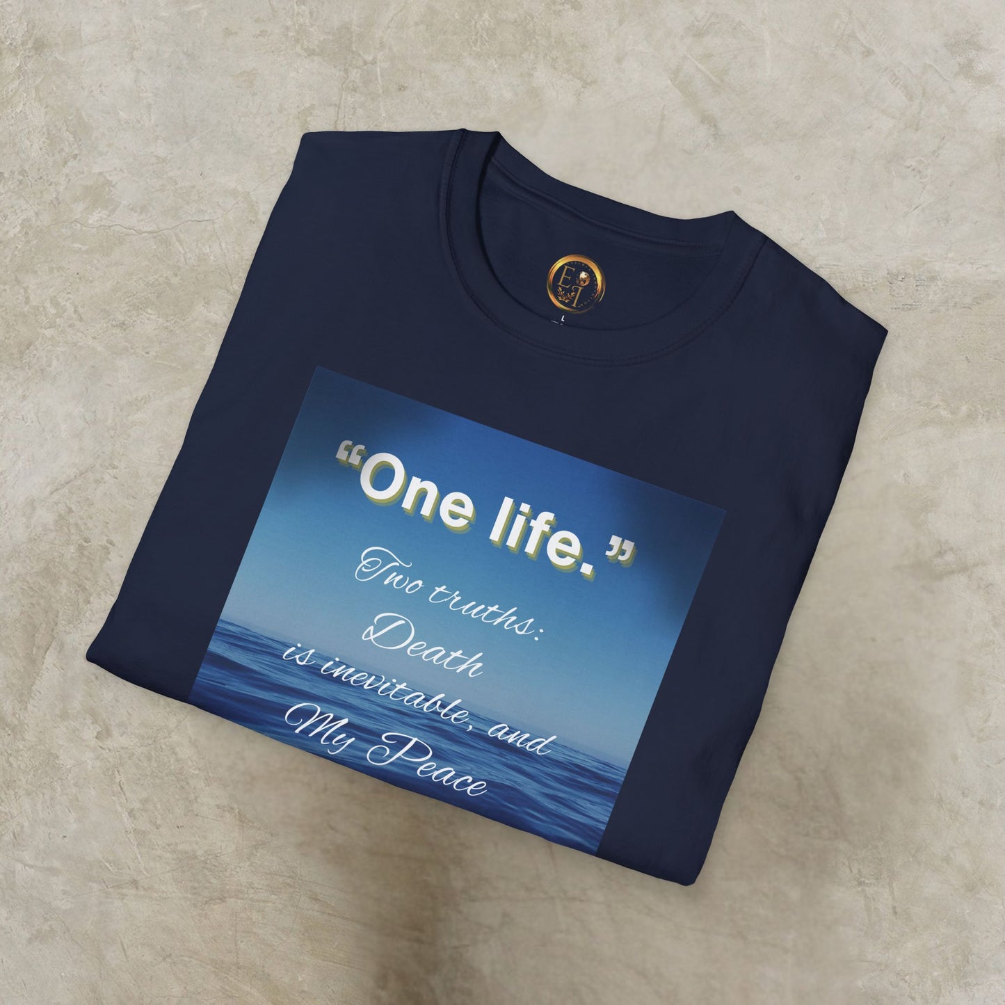 Folded navy blue 'One Life' t-shirt with a blue graphic and text on a beige surface