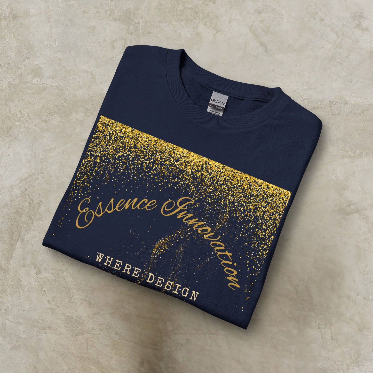 Folded navy blue t-shirt with gold Essence Innovation 'Design Meets Soul' text on a beige surface