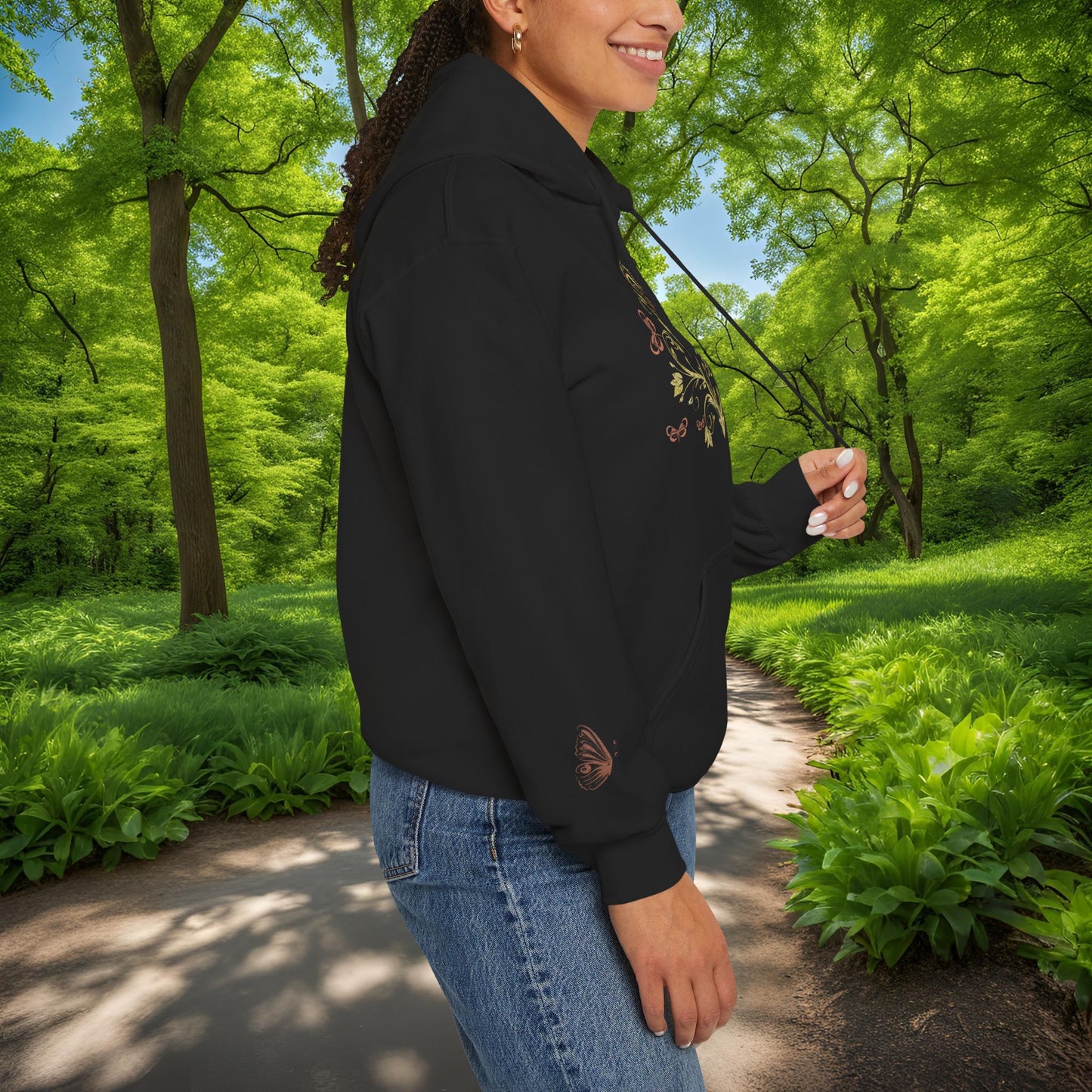 Person wearing a black Essence Innovation Bohemian Butterfly Crest hoodie with embroidery in a park setting