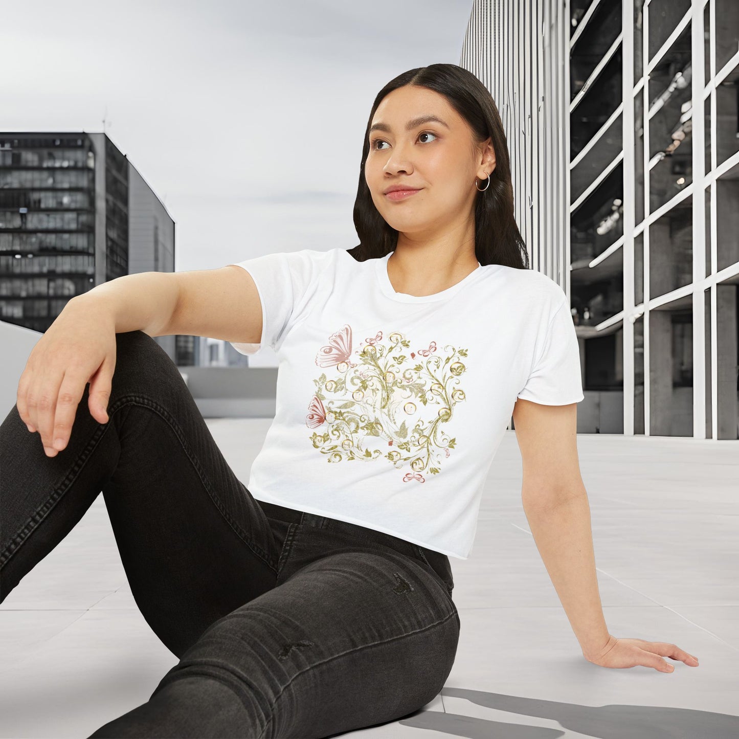 Woman wearing a white t-shirt with a Essence Innovation Bohemian Butterfly floral design, sitting on a bench in an urban setting.
