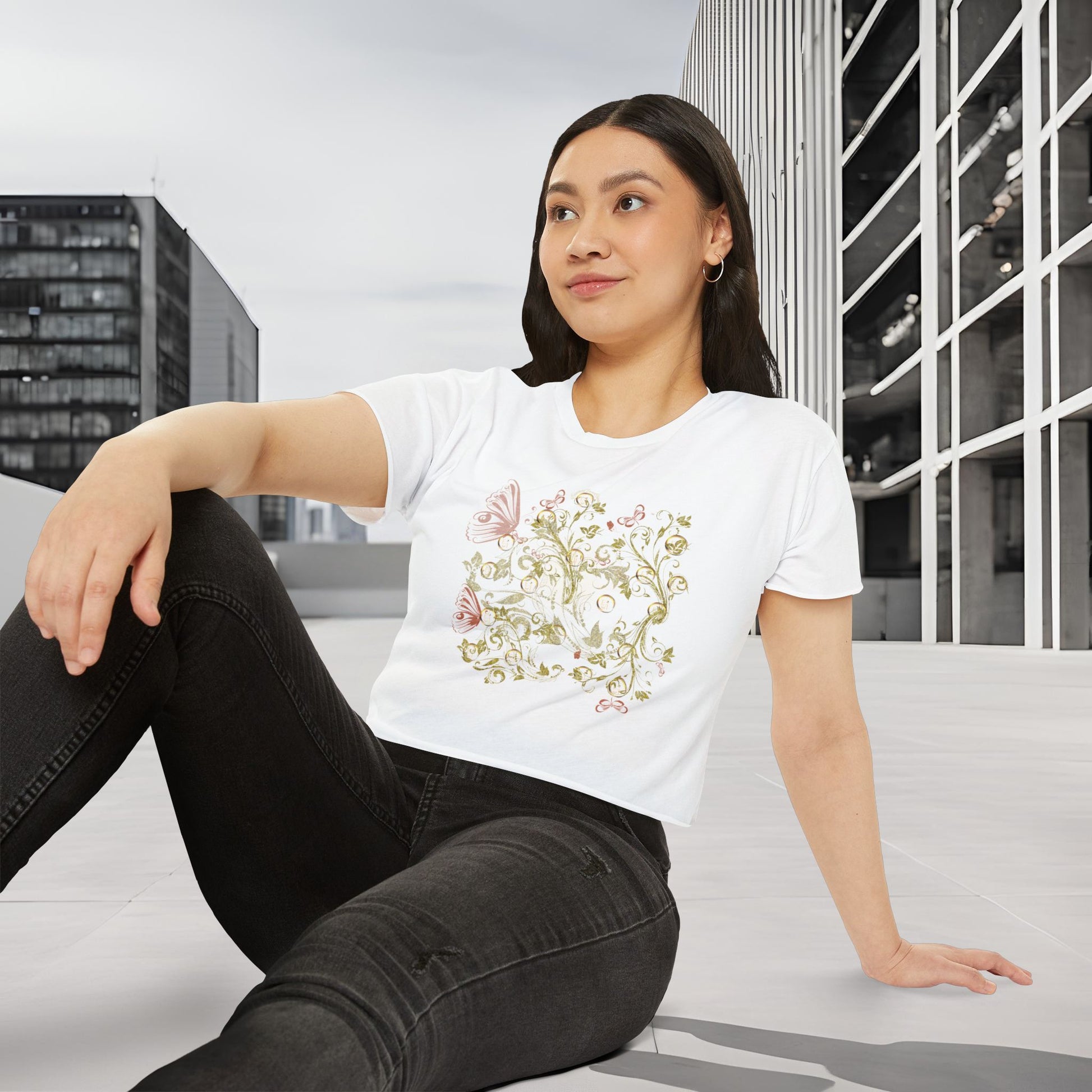 Woman wearing a white t-shirt with a Essence Innovation Bohemian Butterfly floral design, sitting on a bench in an urban setting.