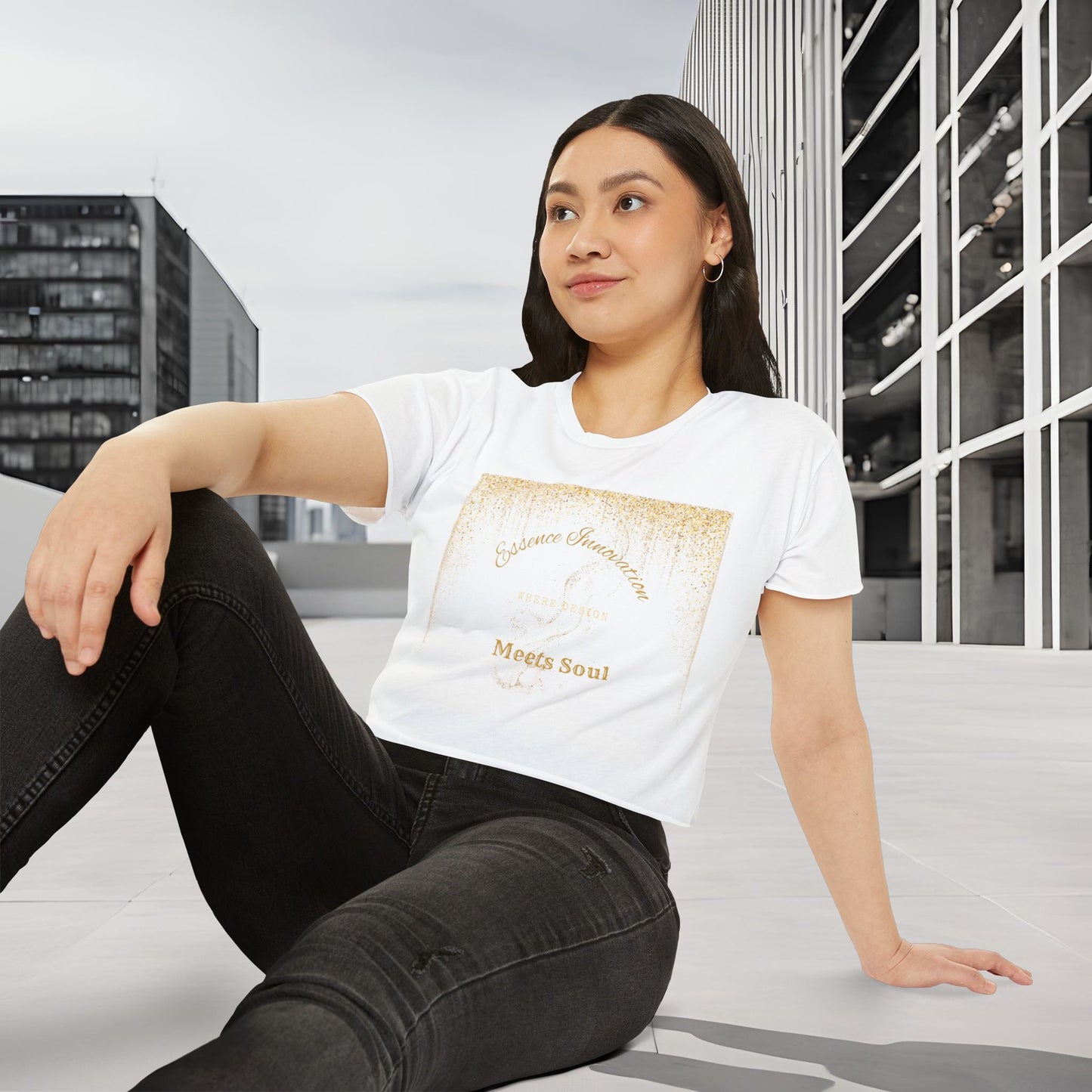 Woman wearing a white t-shirt with Essence Innovation 'Design Meets Soul' text, sitting on a bench in an urban setting.