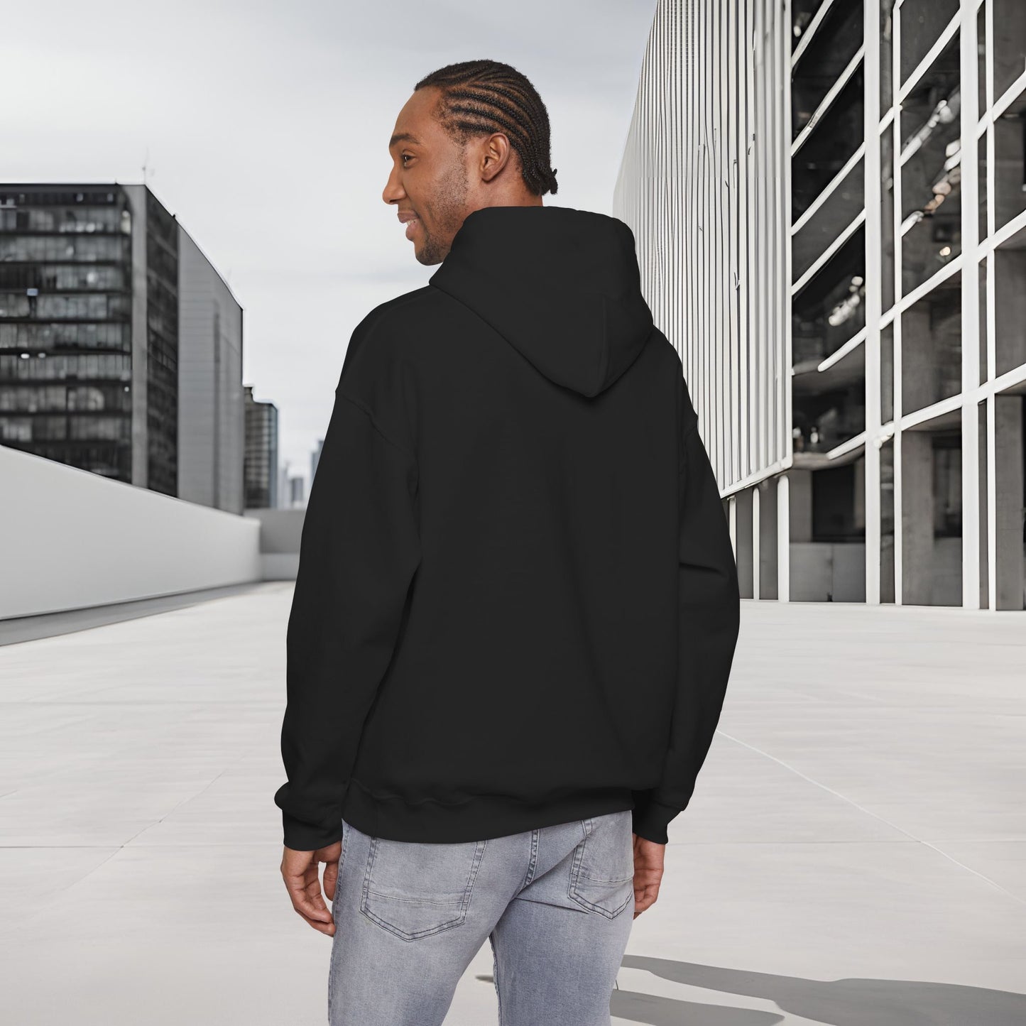 Man wearing a black Essence Innovation 'One Life' hoodie standing on a rooftop with modern buildings in the background