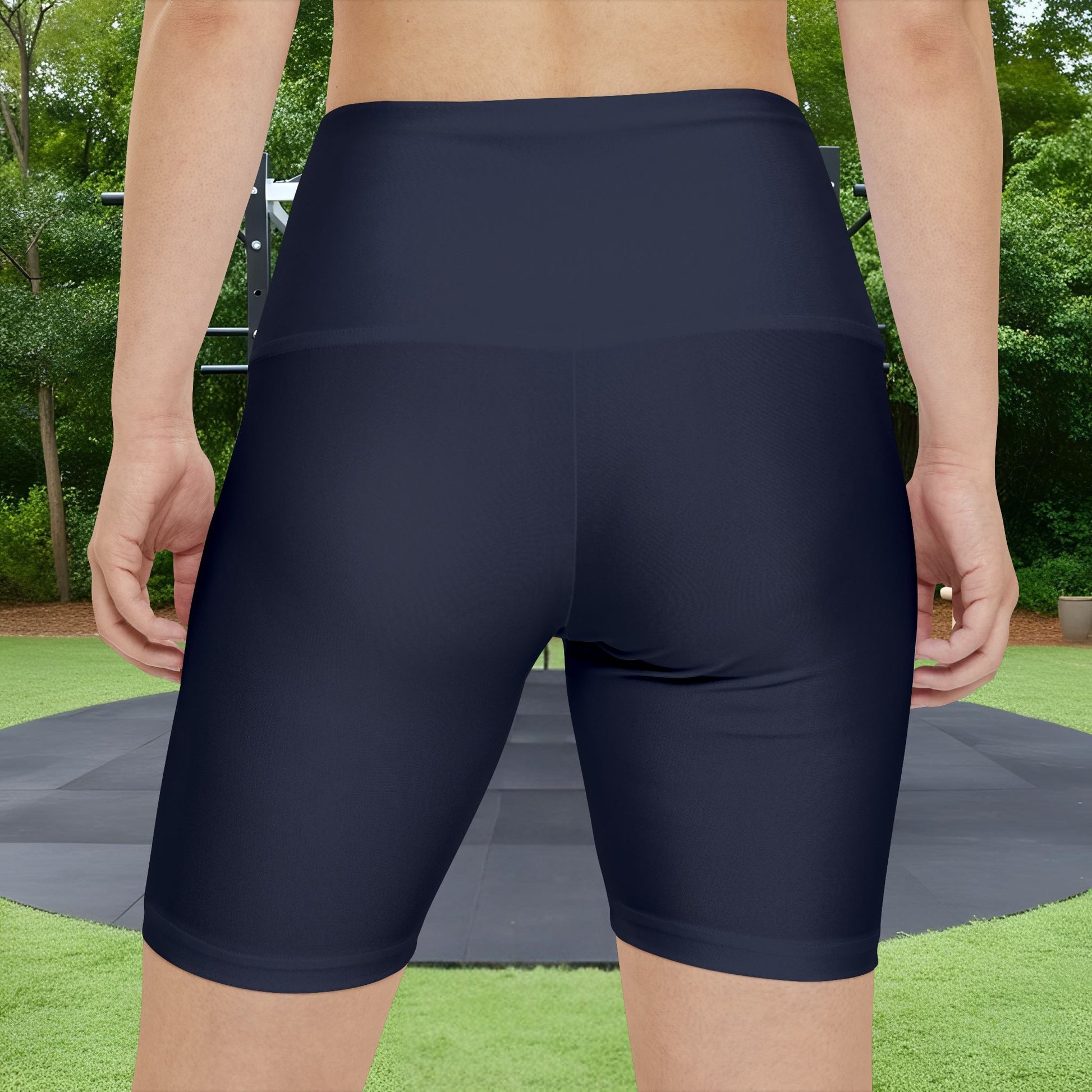 Person wearing navy blue athletic shorts with a blurred green outdoor background