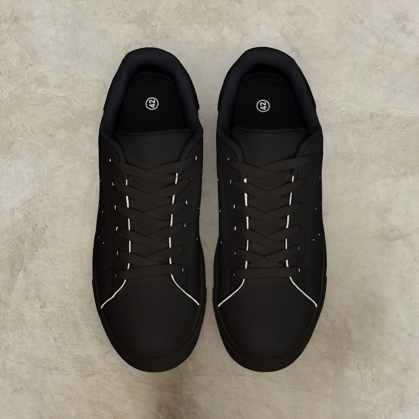 Pair of black EssenceInnoCreate sneakers on a beige surface