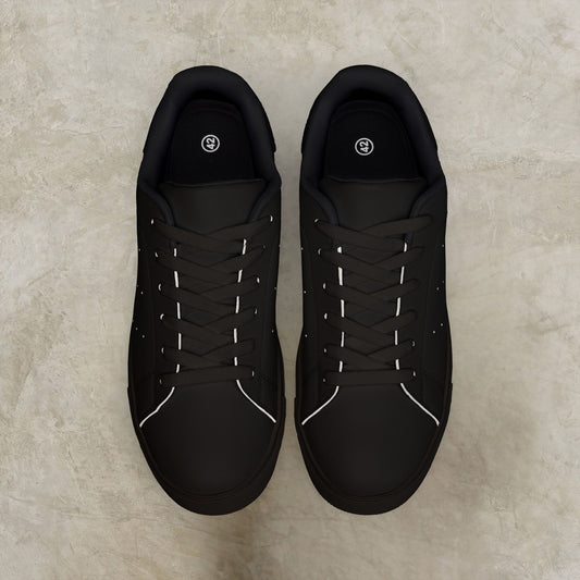 Pair of black EssenceInnoCreate sneakers on a beige surface