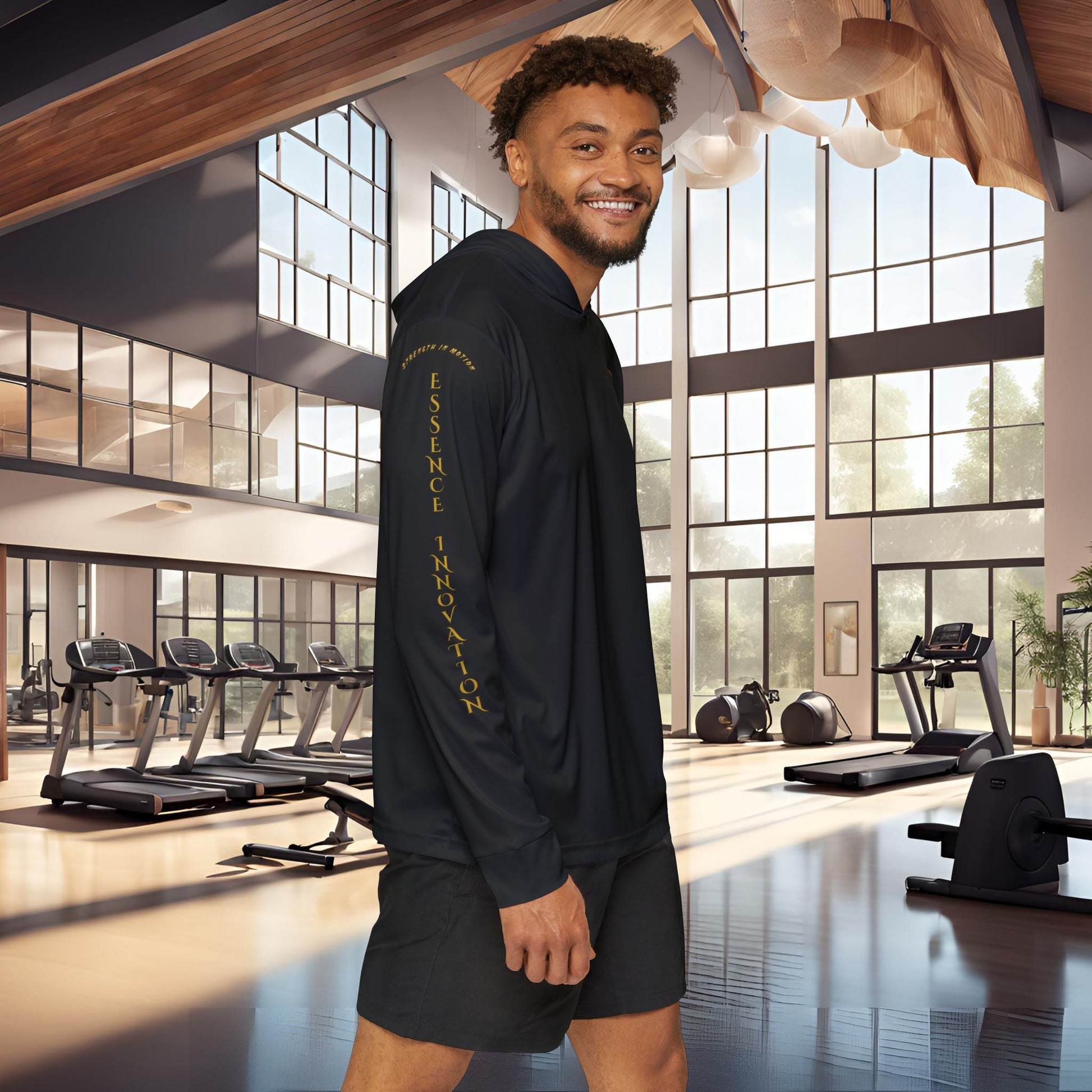 Man wearing a black Essence Innovation Seek More hoodie with text in a modern gym setting