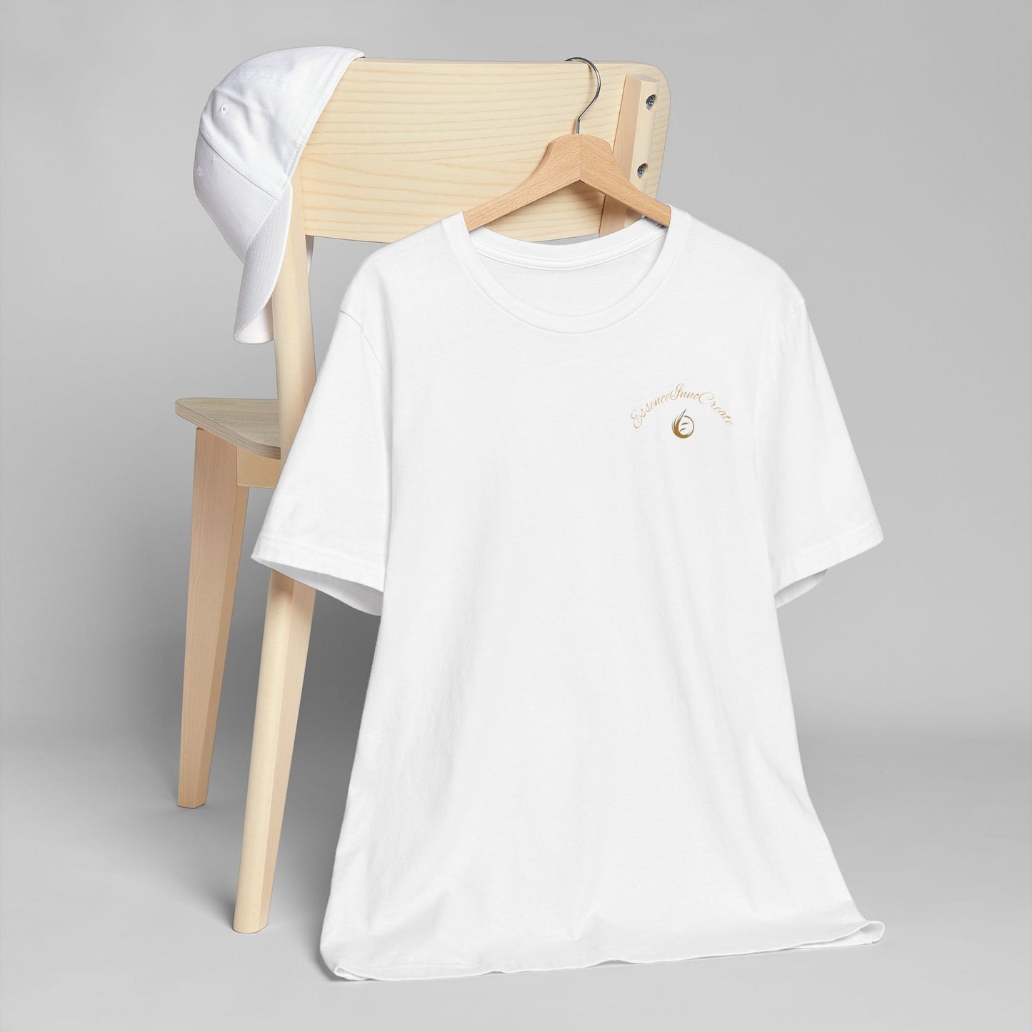 White t-shirt with 'EssenceInnoCreate' logo on a wooden chair against a gray background