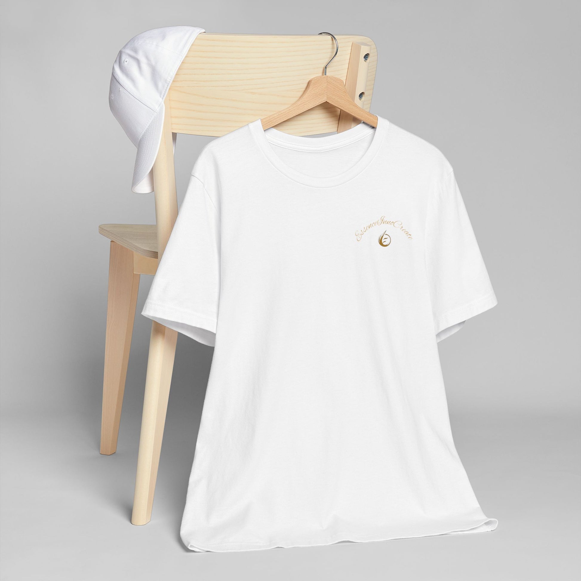 White t-shirt with 'EssenceInnoCreate' logo on a wooden chair against a gray background