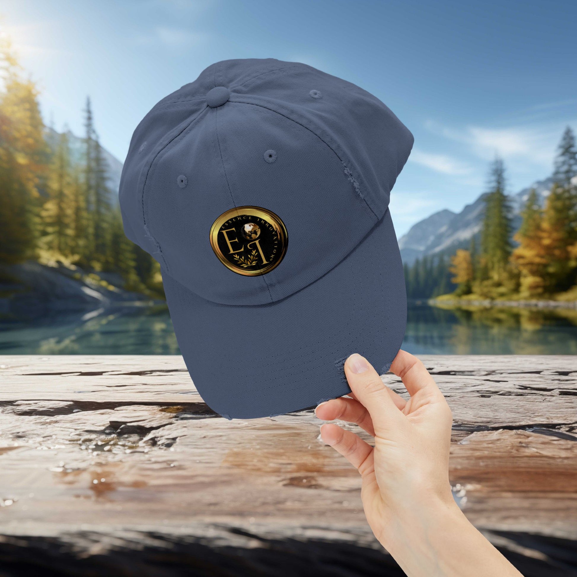 Blue Essence Innovation cap with a logo held by a hand against a scenic background of trees and water.