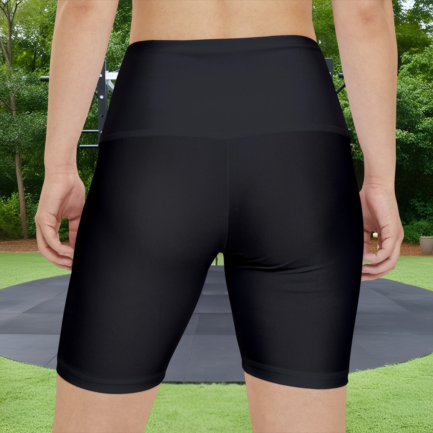 Person wearing black athletic shorts with a green outdoor background