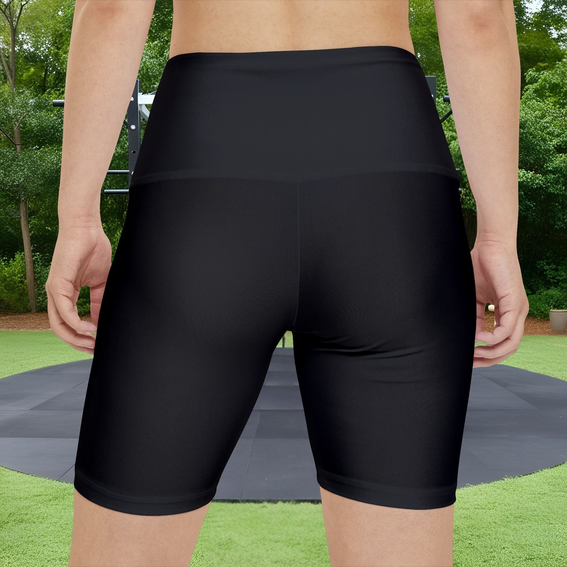 Person wearing black athletic shorts with a green outdoor background
