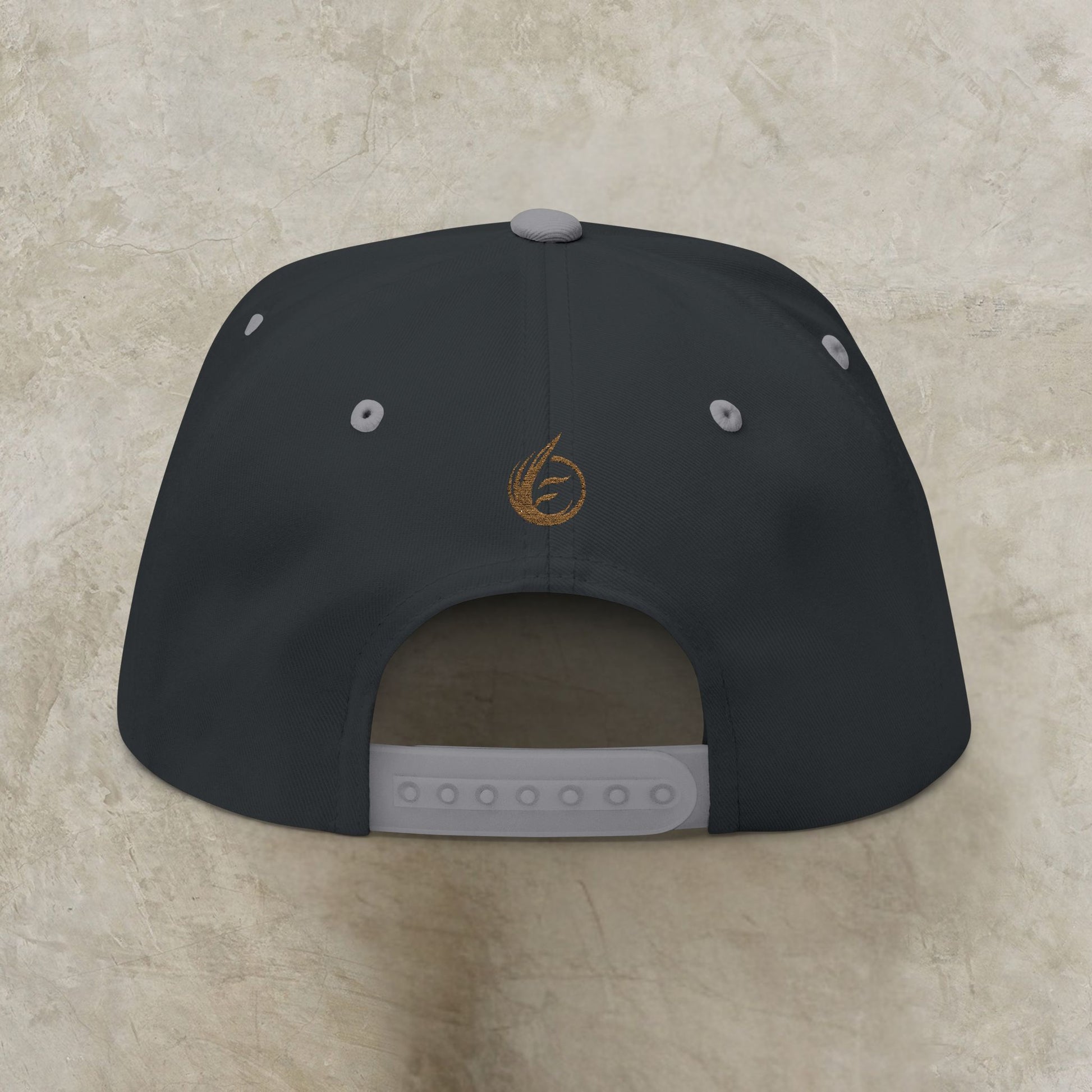 Black cap with a EssenceInnoCreate logo on the back against a beige background