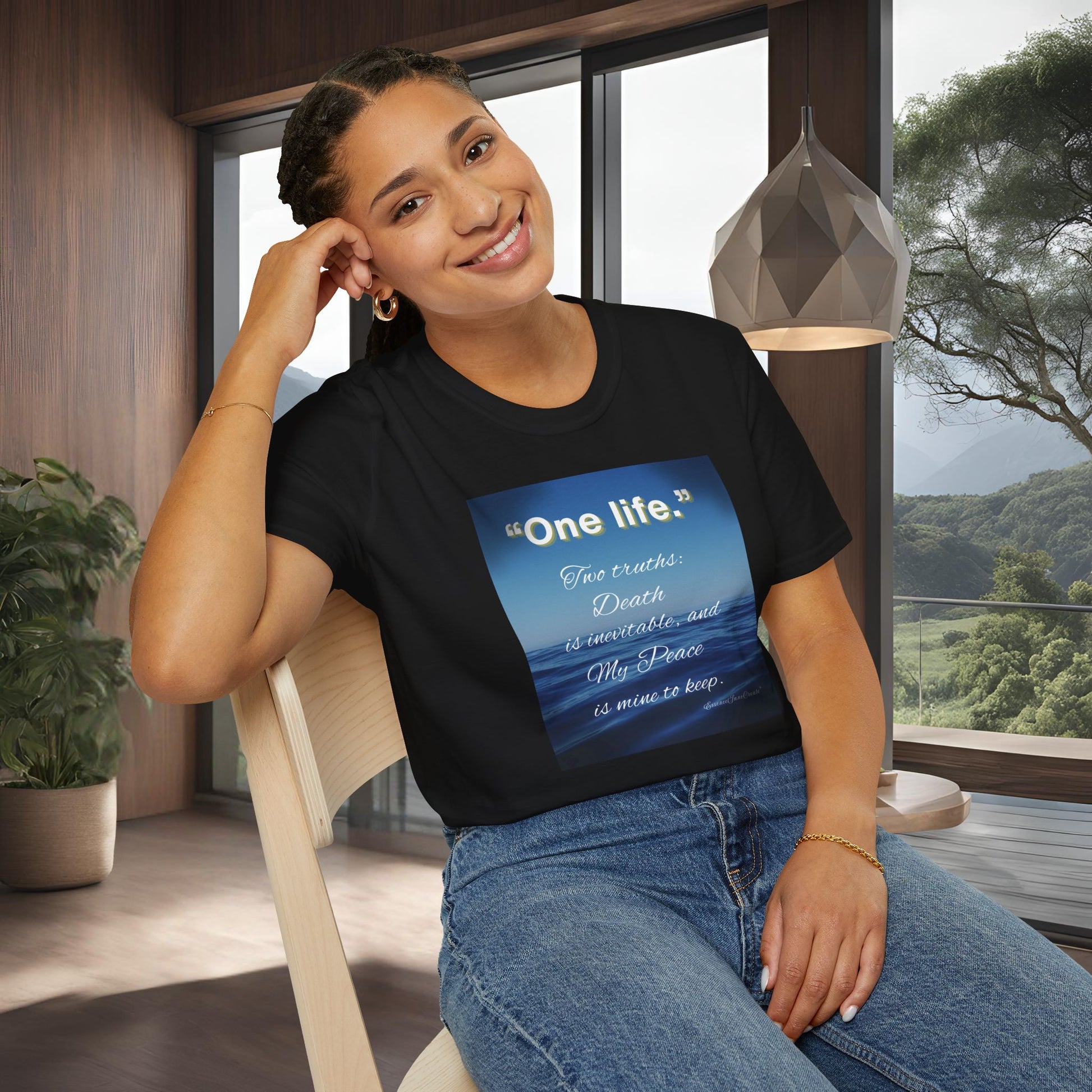 Woman wearing a black 'One Life' t-shirt with a blue graphic and text, sitting indoors.