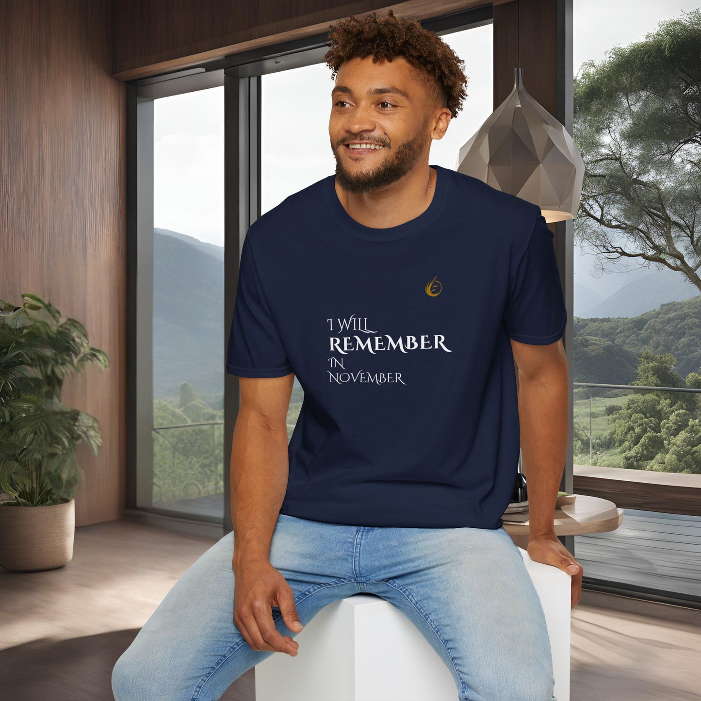 Man wearing a navy blue EssenceInnoCreate Quiet Resolve t-shirt with text, sitting in a modern room with large windows.