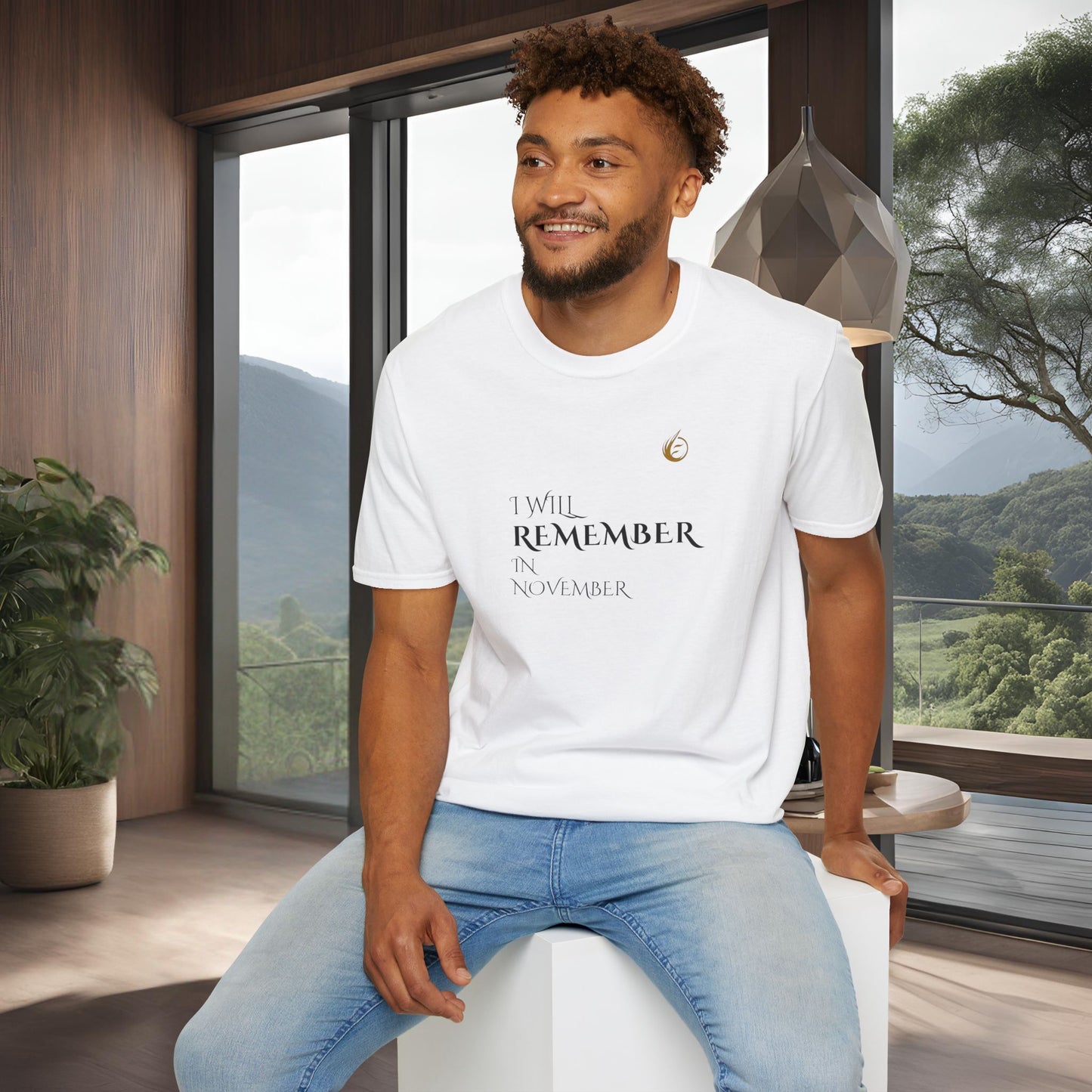 Man wearing a white EssenceInnoCreate Quiet Resolve t-shirt with text, sitting in a modern room with large windows.