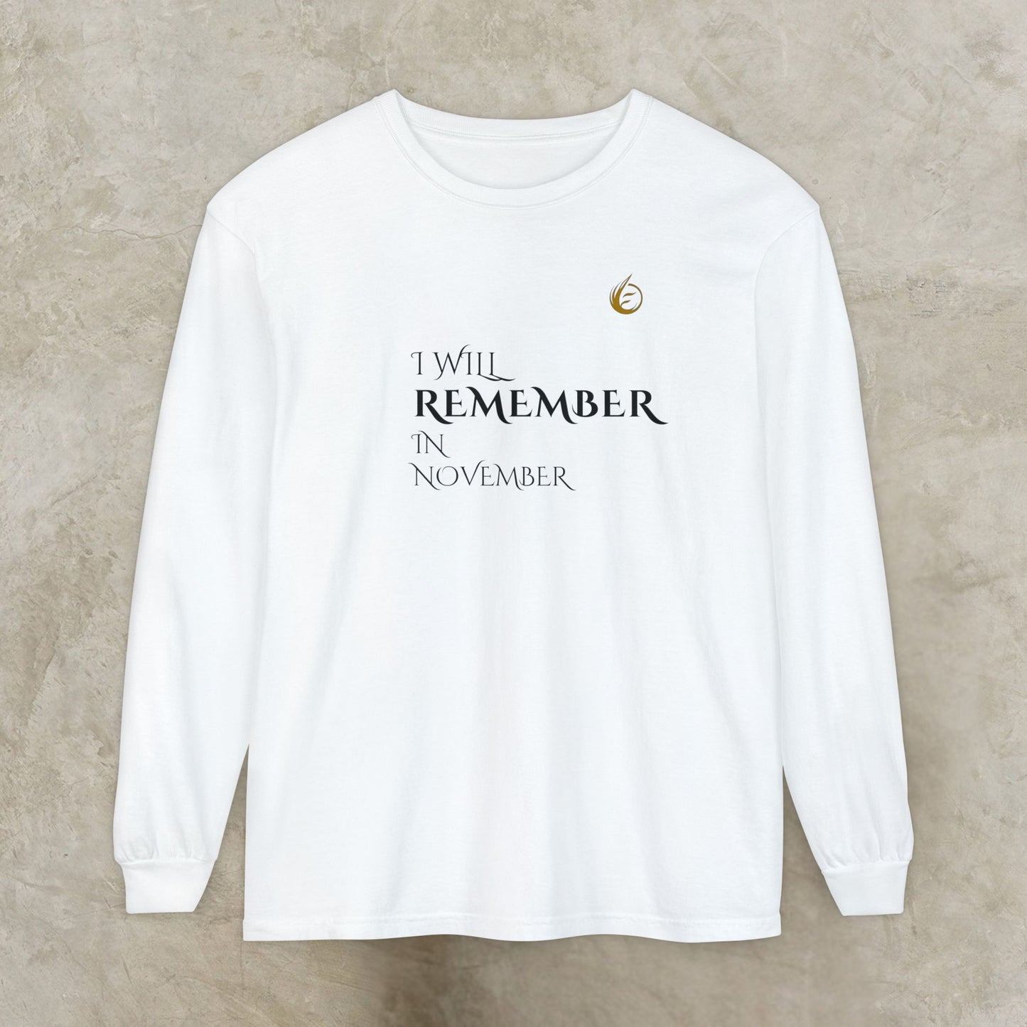 White long-sleeve EssenceInnoCreate Quiet Resolve shirt with text 'I WILL REMEMBER IN NOVEMBER' on a beige background