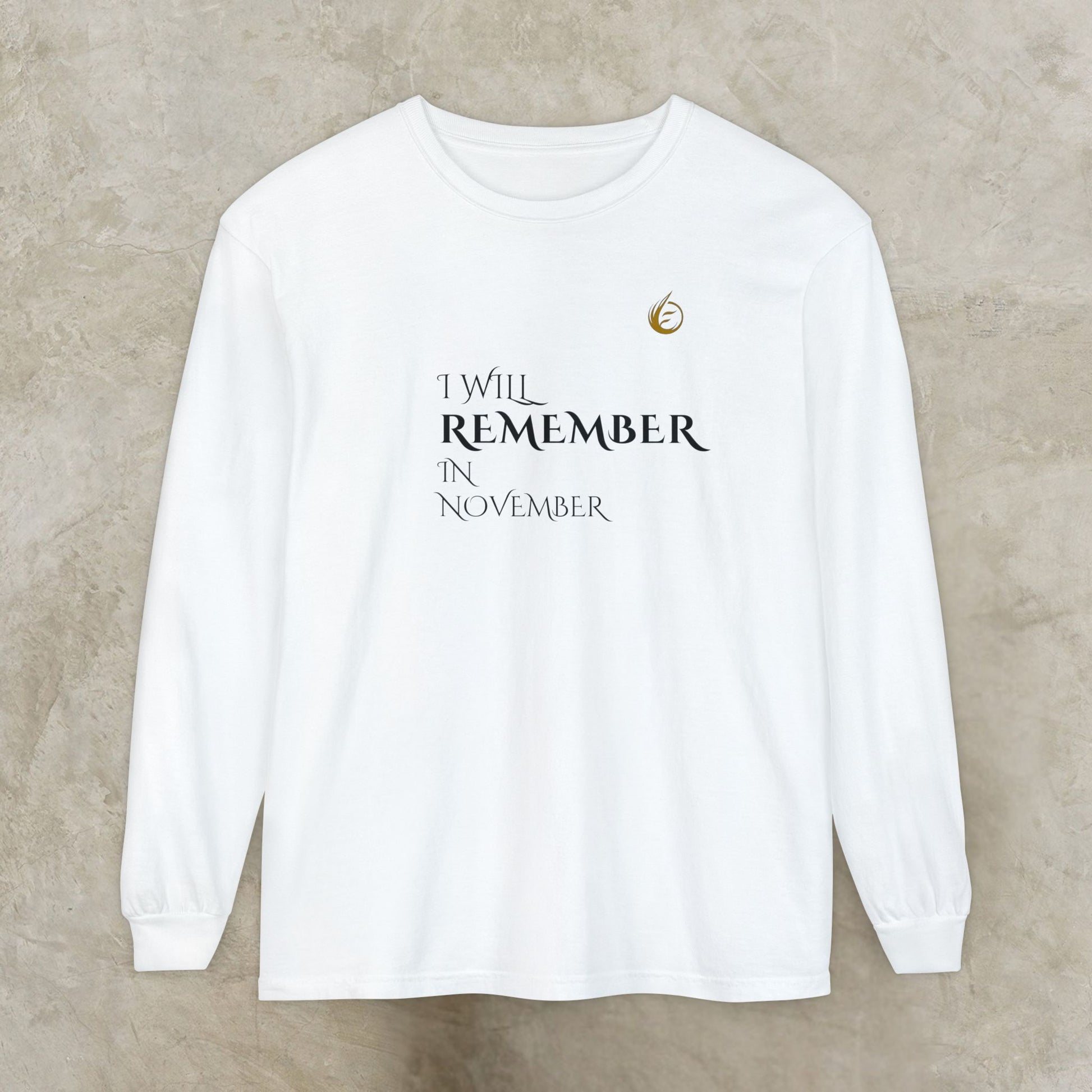 White long-sleeve EssenceInnoCreate Quiet Resolve shirt with text 'I WILL REMEMBER IN NOVEMBER' on a beige background