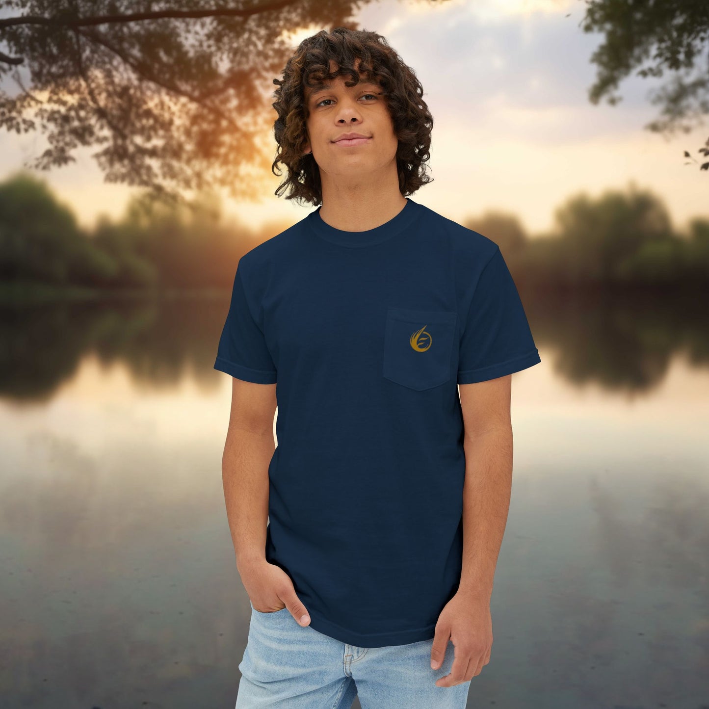 Person wearing a navy blue t-shirt with an 'EssenceInnoCreate' logo, standing by a body of water during sunset.