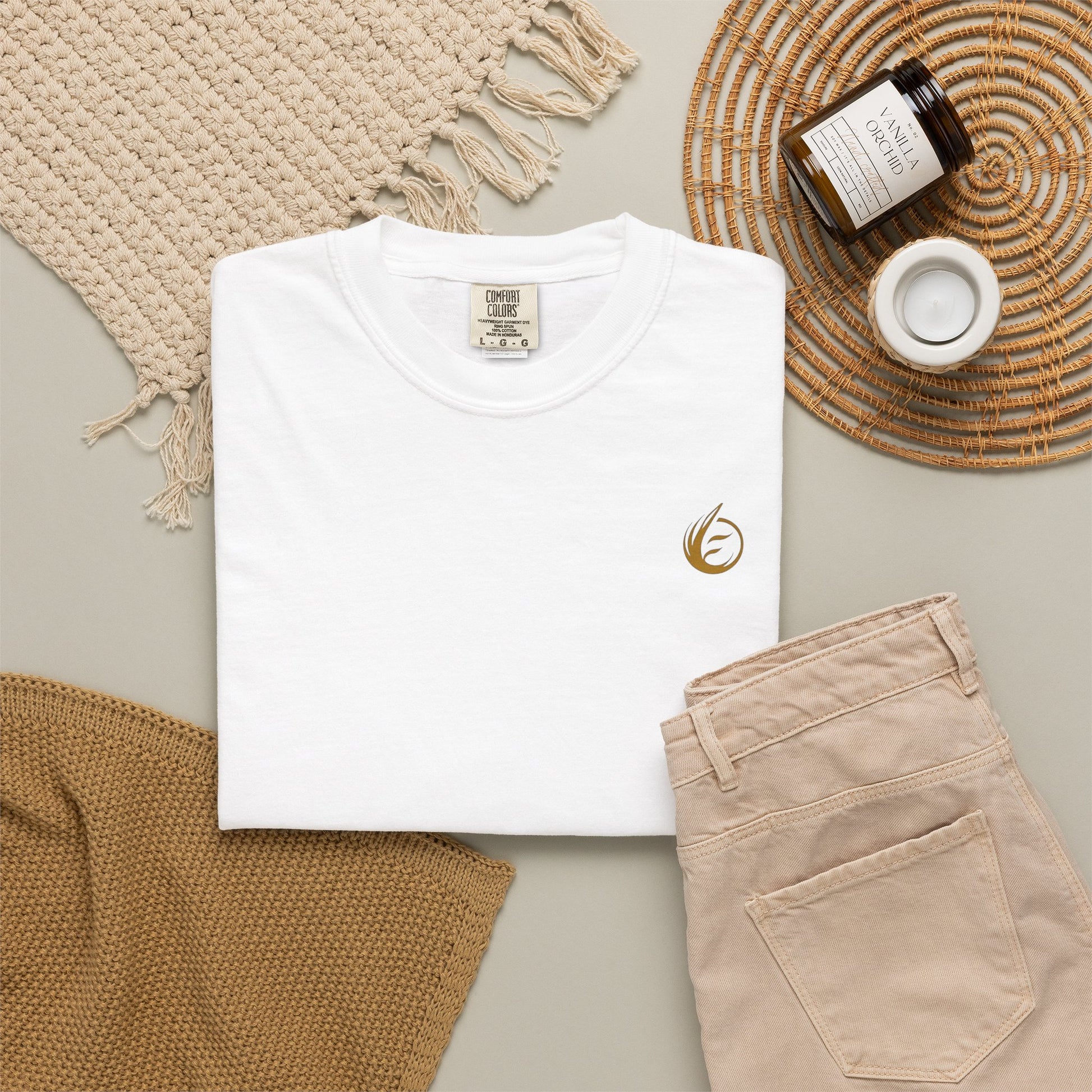 White t-shirt with 'EssenceInnoCreate' text, beige pants, and decorative items on a neutral background