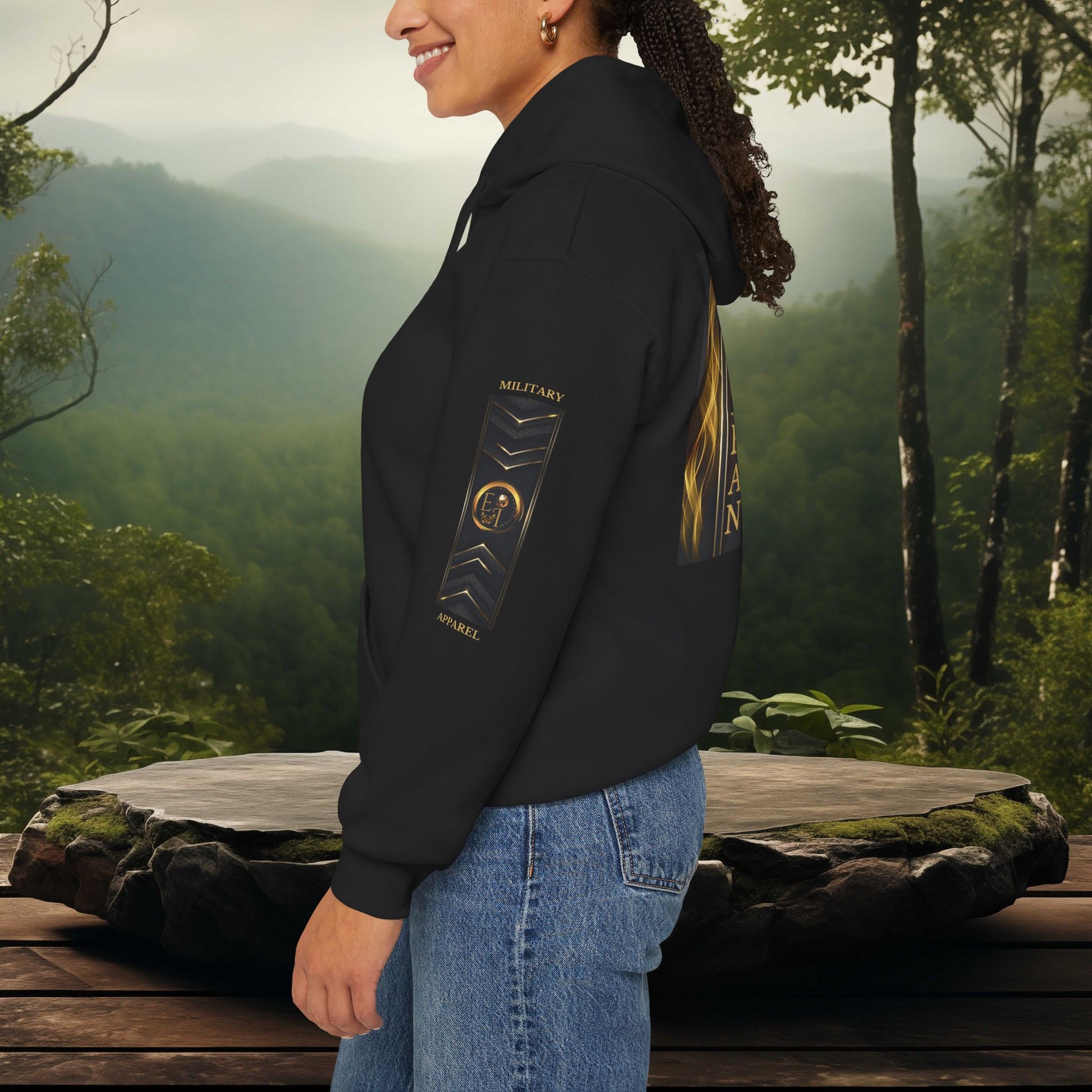 Person wearing a black Essence Innovation hoodie with a military apparel design in a forest setting
