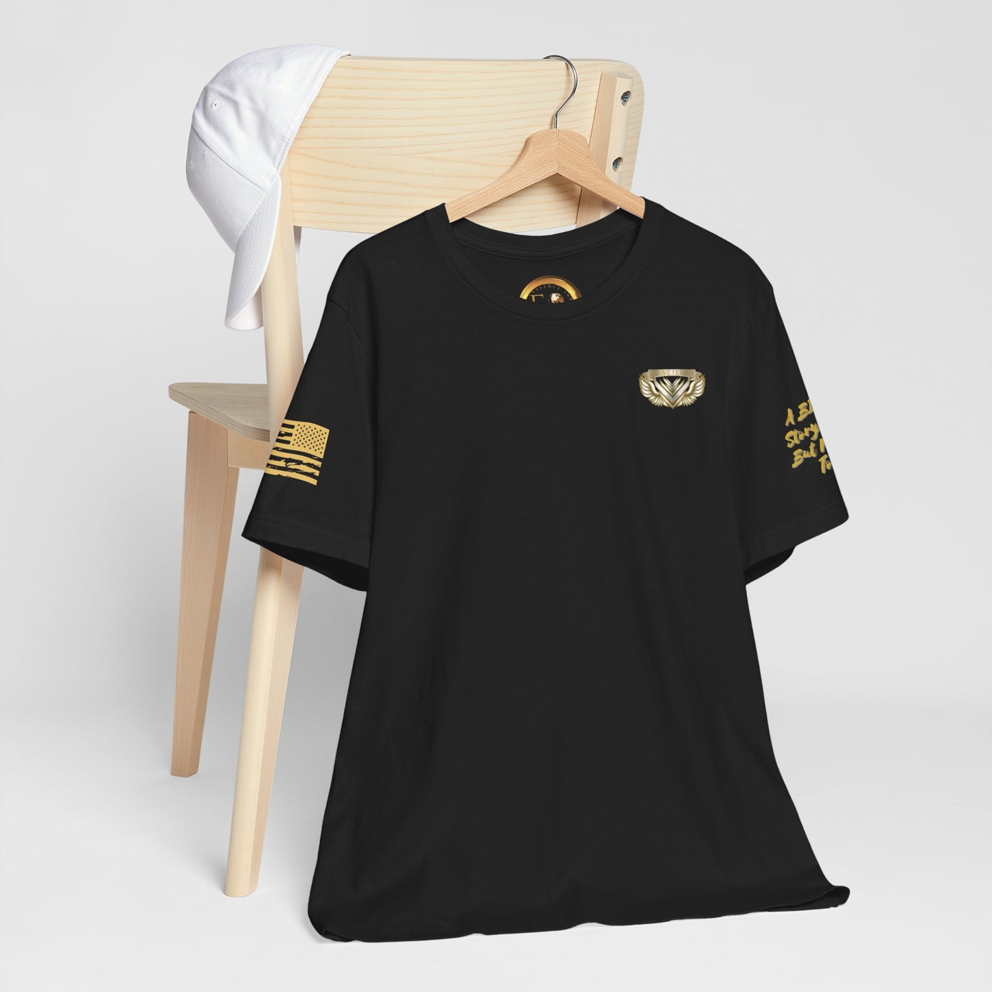 Black t-shirt with gold designs on a wooden chair against a white background