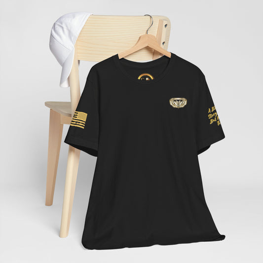 Black t-shirt with gold designs on a wooden chair against a white background