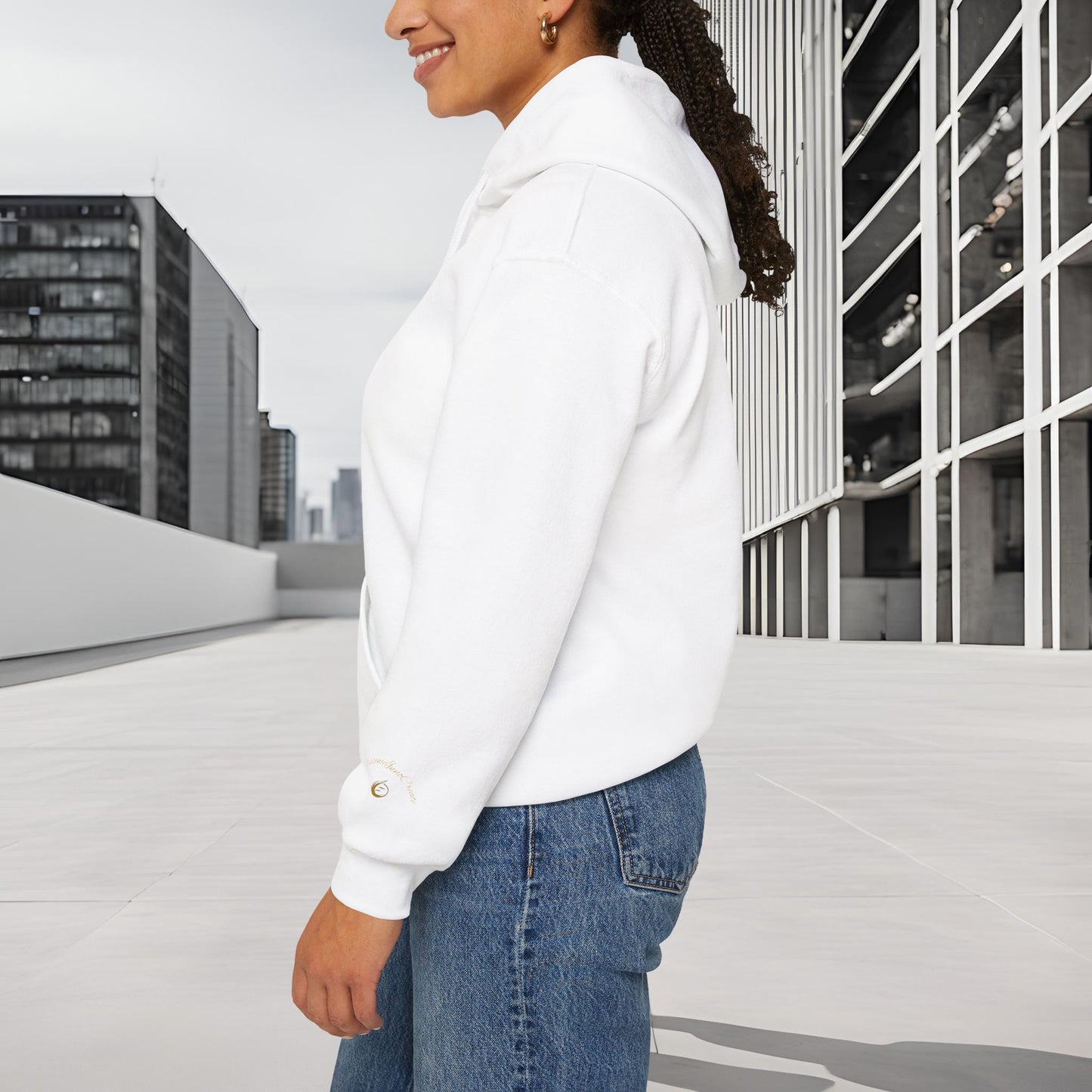 Person wearing a white 'EssenceInnoCreate' hoodie and blue jeans standing on a rooftop with cityscape background