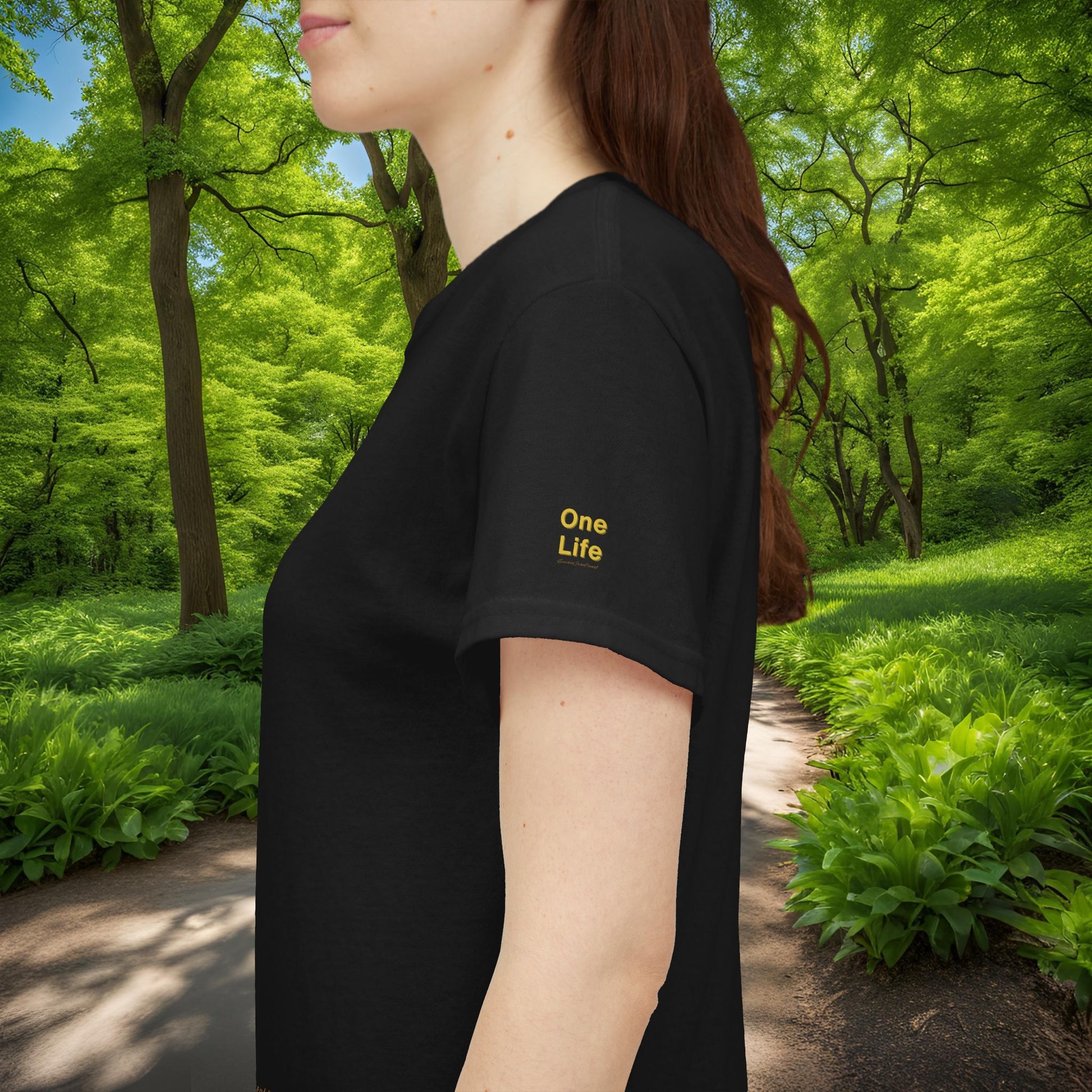 Person wearing a black t-shirt with 'One Life' text in a forest setting
