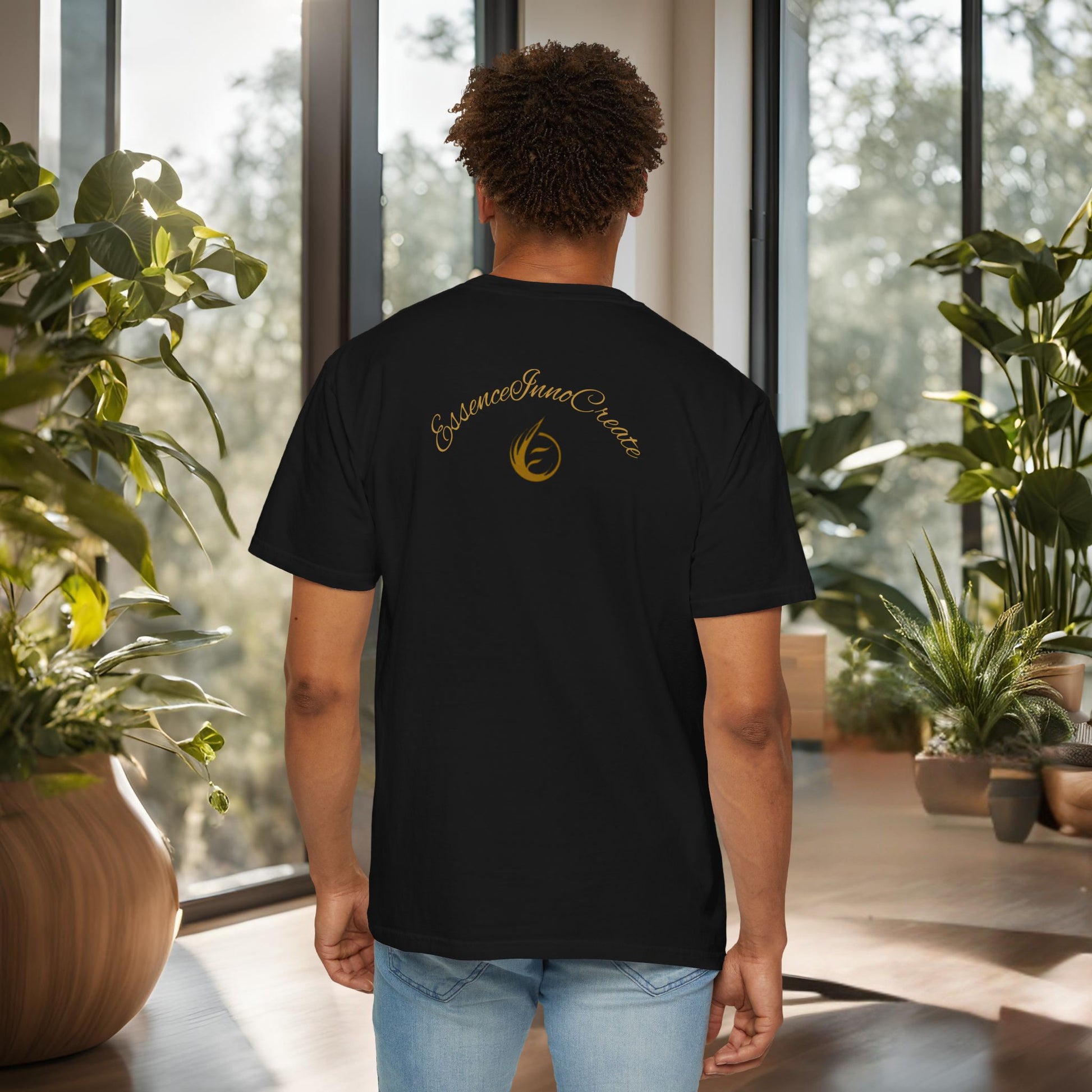 Person wearing a black t-shirt with 'EssenceInnoCreate' logo in an indoor setting with plants