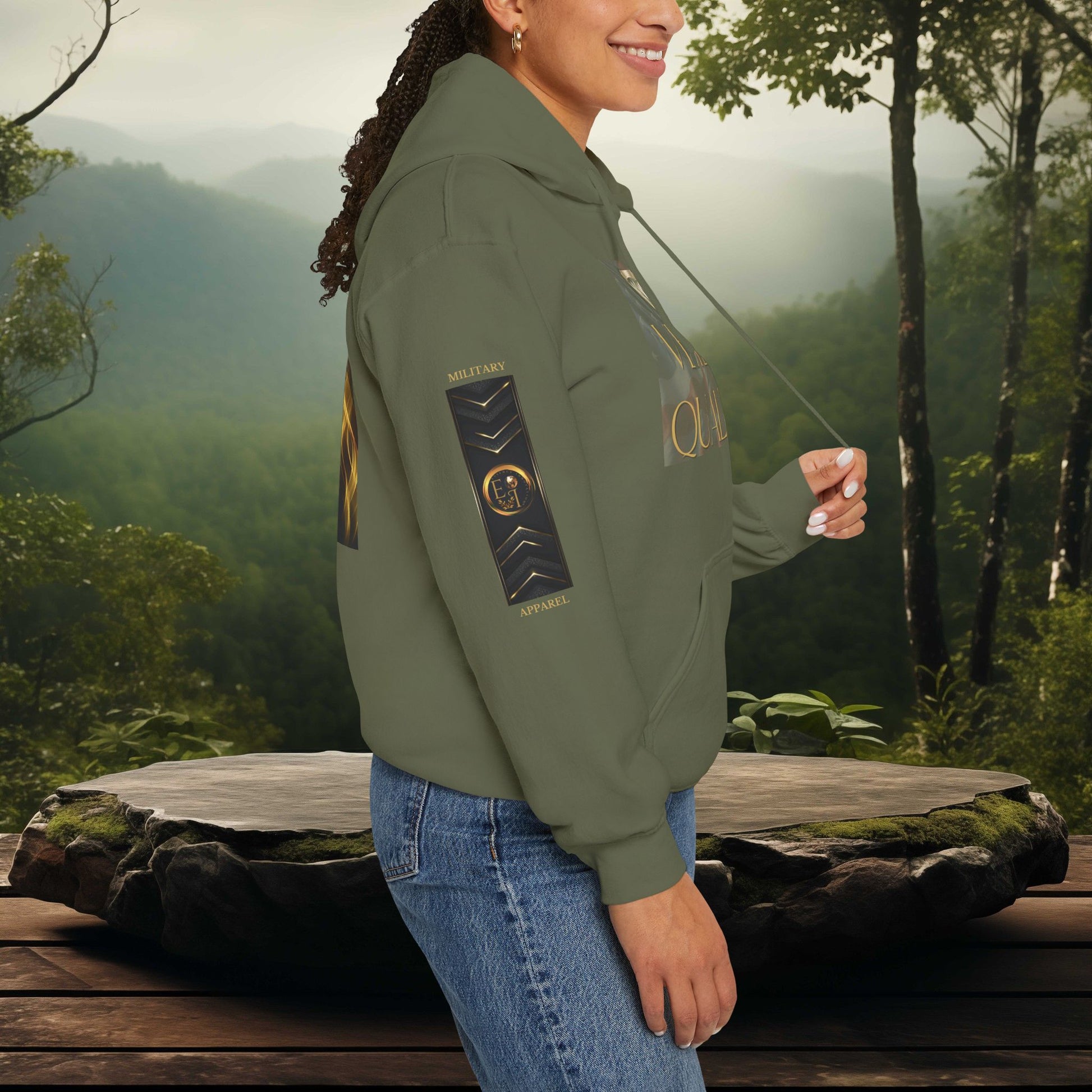 Person wearing a green Essence Innovation hoodie with a veteran-themed design, standing in a forest setting.