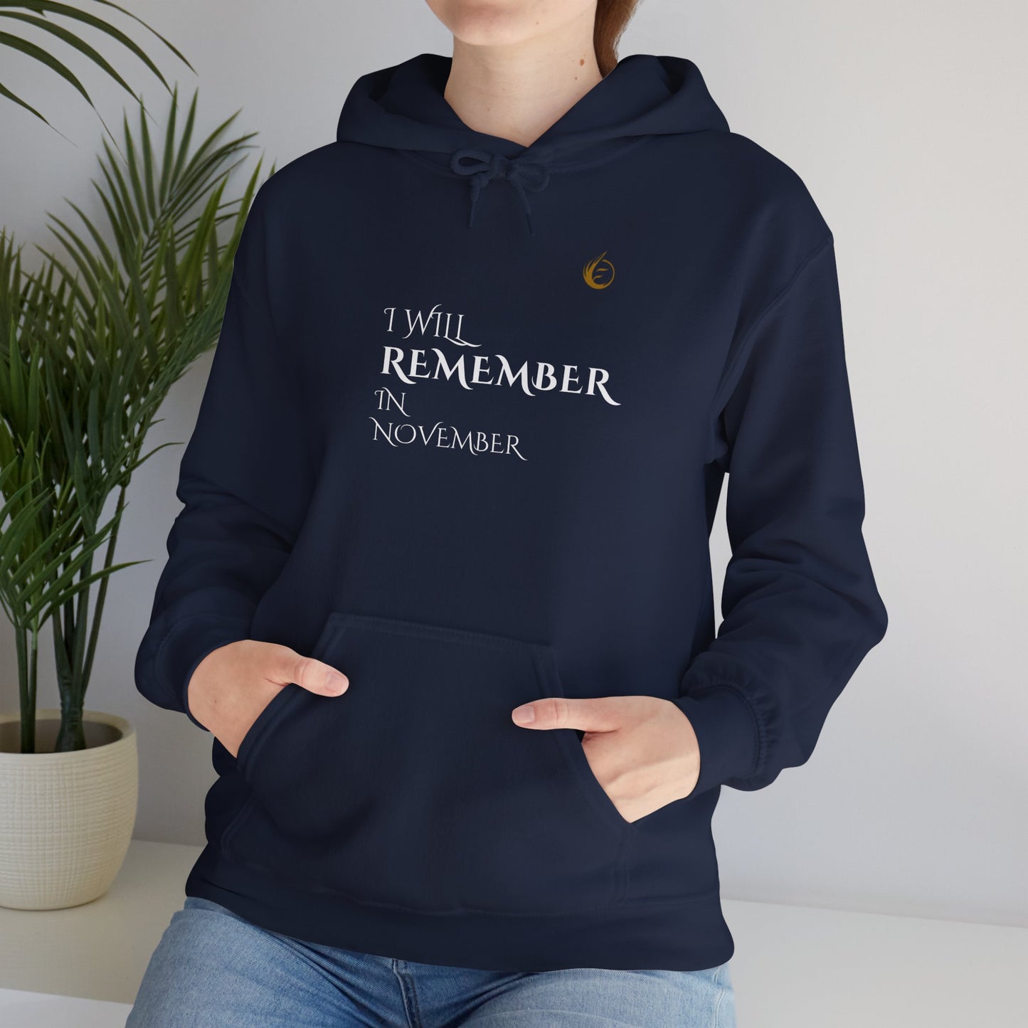 Person wearing a brown EssenceInnoCreate Quiet Resolve hoodie with a plant in the background
