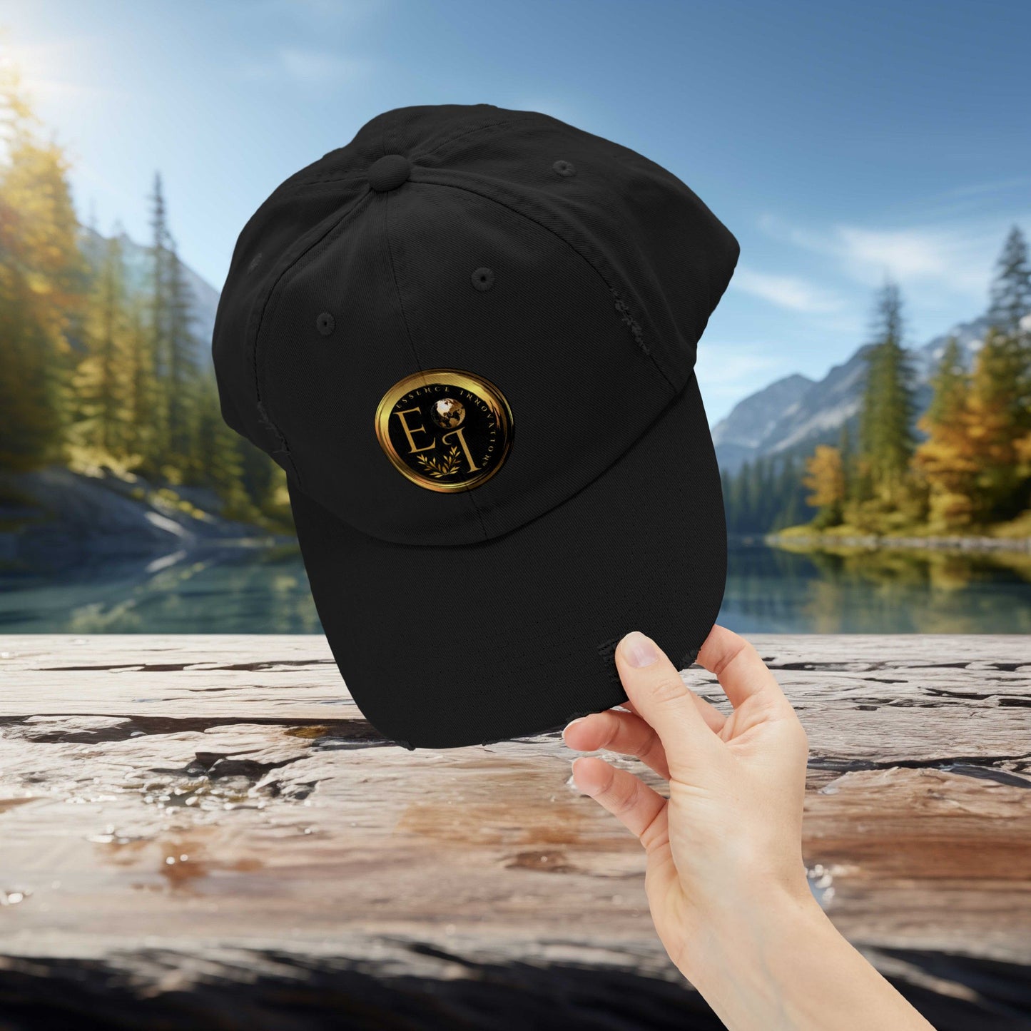Black Essence Innovation cap with a gold logo held by a hand against a scenic background of trees and water.