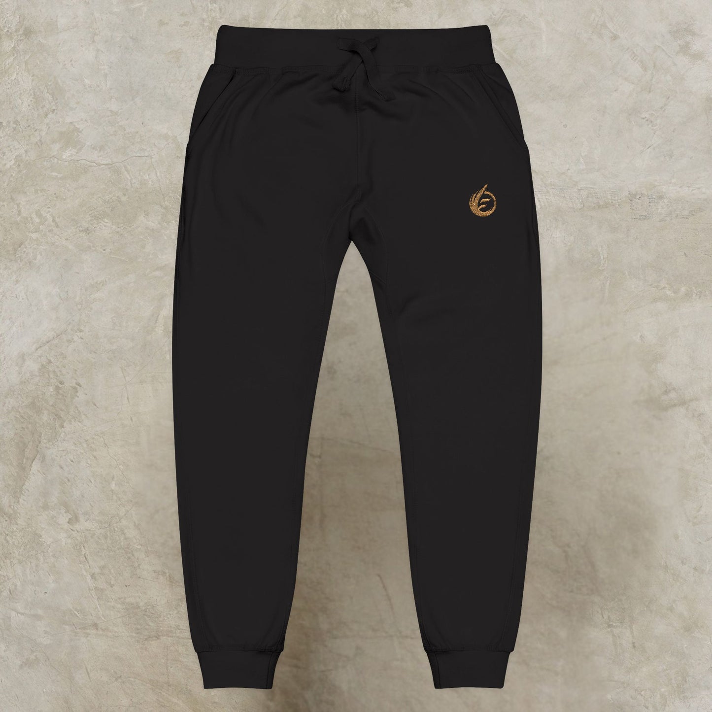 Black 'EssenceInnoCreate' Quiet Resolve jogger pants with a logo on a beige background