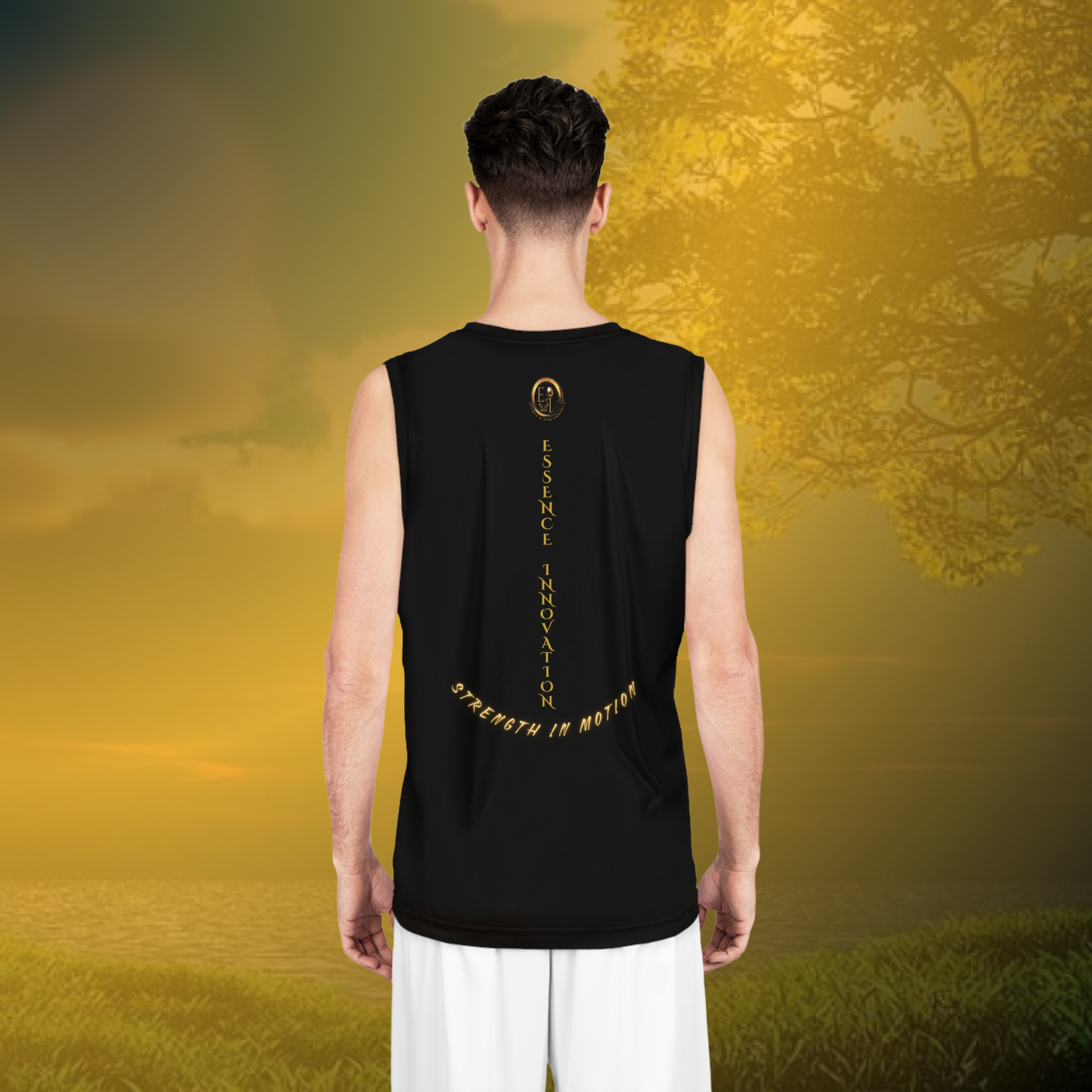 Person wearing a black sleeveless shirt with text standing in a field with a tree and sunset in the background